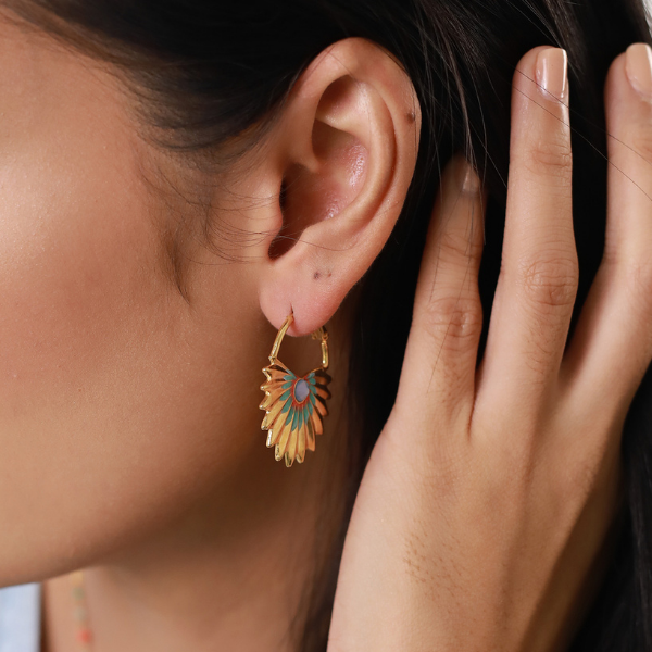 Image of model wearing creole, fan palm leaf earrings gilded with 18k gold and turquoise and coral enamel.