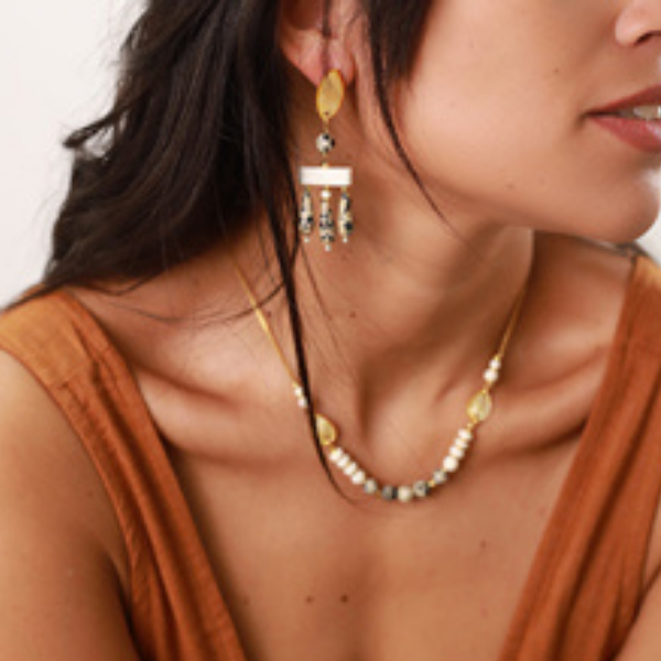 Image of model wearing drop earrings with mother of pearl shaped leaf, dalmatian jasper dangles and bone elements. Set as stud or clip-on.