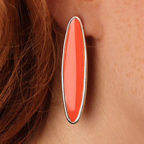 Image of model wearing elongated oval shape earrings enamelled in pink on silver stud finish.