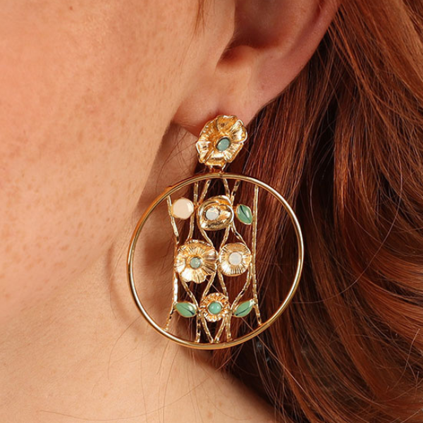 Image of model wearing elegant golden creole dangle earrings embellished with different shaped flowers using rhinestone as centrepiece on gold metal finish.