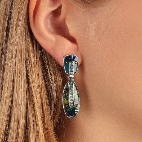 Image of model wearing oval dangle earrings encrusted with hand painted patterns and stones.